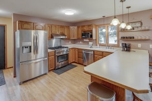 A modern kitchen with stainless steel appliances, wooden cabinets, and a central island.