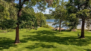 A grassy area with trees and a lake in the background.