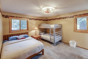 A bedroom with a bunk bed, a single bed, a nightstand, a lamp, and a window. - Blue Flag Shores Private Home (Pequot Lakes)