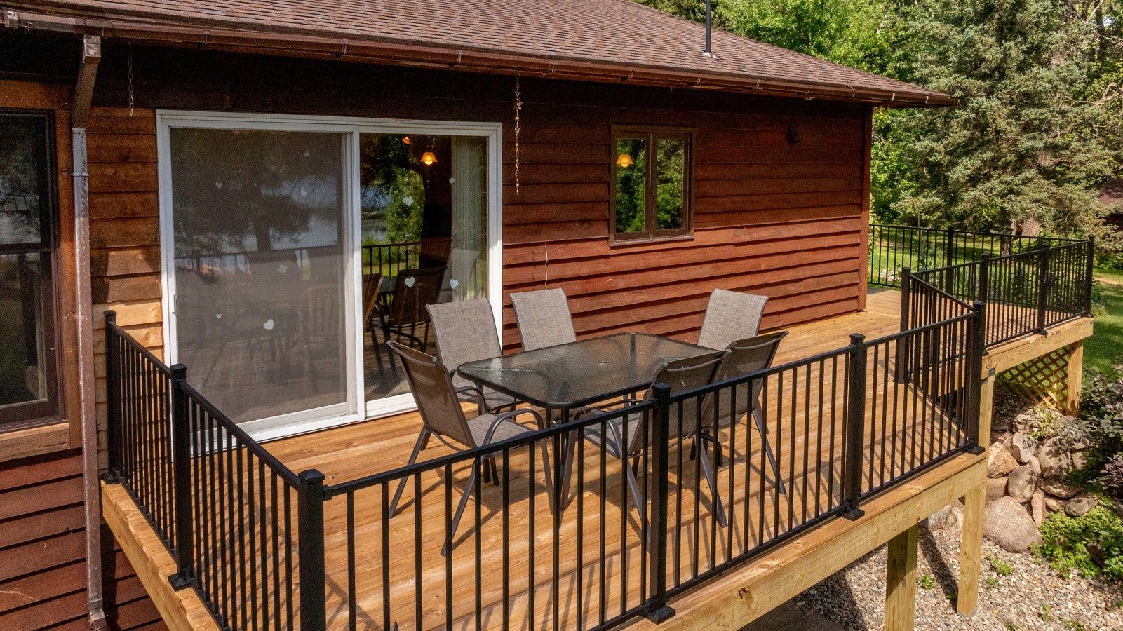 Eine Holzhütte mit einer Veranda, einer Glastür zu einer Terrasse und einem Tisch mit Stühlen.