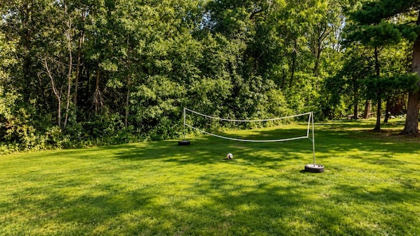 A grassy area with a rope barrier and a volleyball.