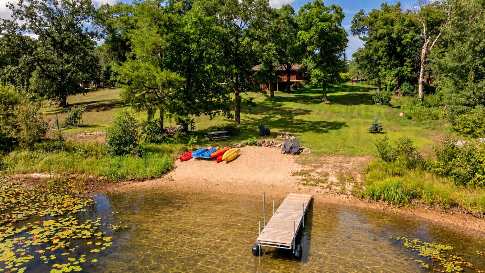 A lakeside property with a dock, kayaks, and a picnic area.