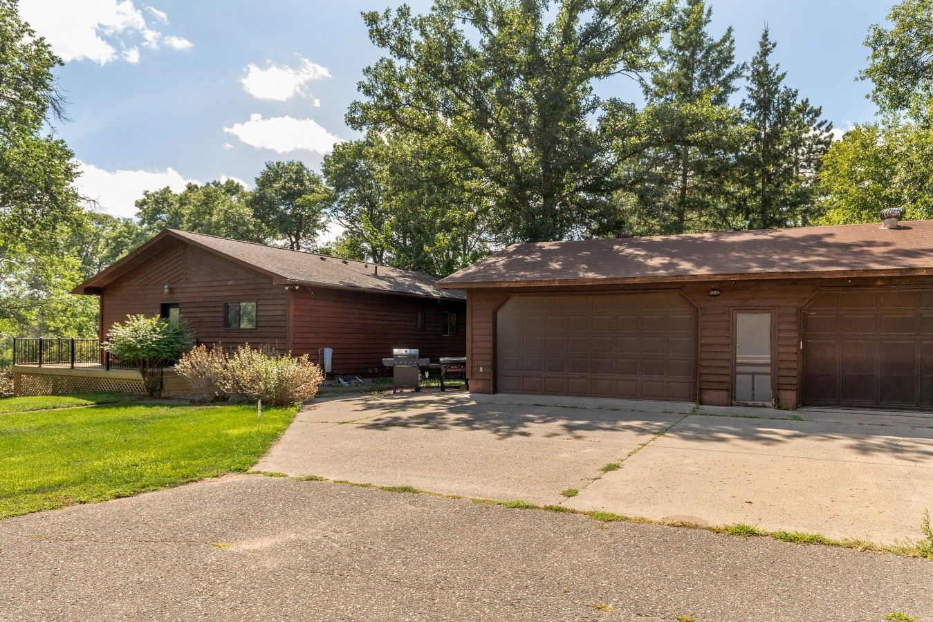 A two-story building with a garage, a covered patio, and a lawn.