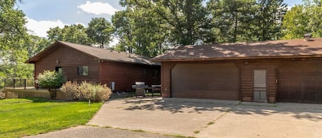 A two-story building with a garage, a covered patio, and a lawn.