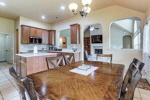 Una cocina amplia con armarios de madera, una isla central y un comedor con mesa y sillas de madera.