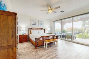 Ein Schlafzimmer mit einem Bett, Nachttischen, einer Bank und einem Deckenventilator.