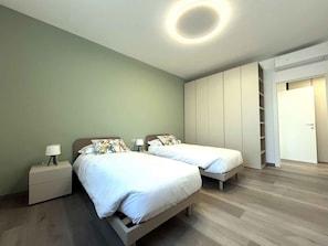 Ein Schlafzimmer mit zwei Betten, einem Kleiderschrank und einer runden Deckenleuchte.