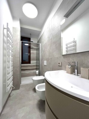 Een moderne badkamer met een gebogen wastafel, een douchecabine met glazen wanden en een toilet.