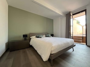 Een slaapkamer met een bed, nachtkastjes en uitzicht.