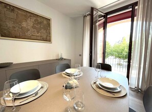 Ein Essbereich mit Tisch für zwei Personen, einem Gemälde an der Wand und Blick durch das Fenster.