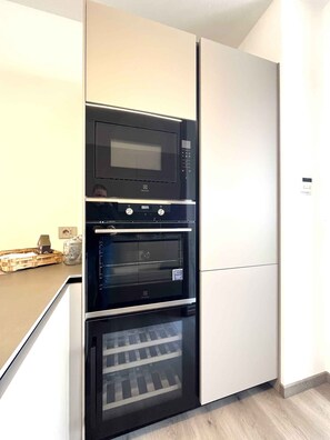 Eine Küche mit Einbau-Mikrowelle, Backofen und Kühlschrank.