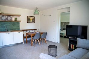 A modern living space with a dining area, kitchen, and a TV in the living room. - Holiday flat with terrace (Lesa)