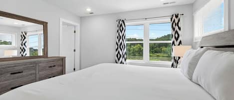 Un dormitorio con una cama grande, un aparador, un espejo y una ventana con cortinas.