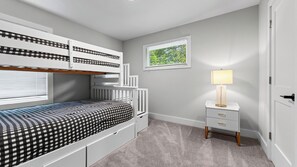 A child's bedroom with bunk beds, a bedside table with a lamp, and a window with blinds. - Sage House by Avantstay Balcony + River Views + Full Kitchen River Arts District (Asheville)