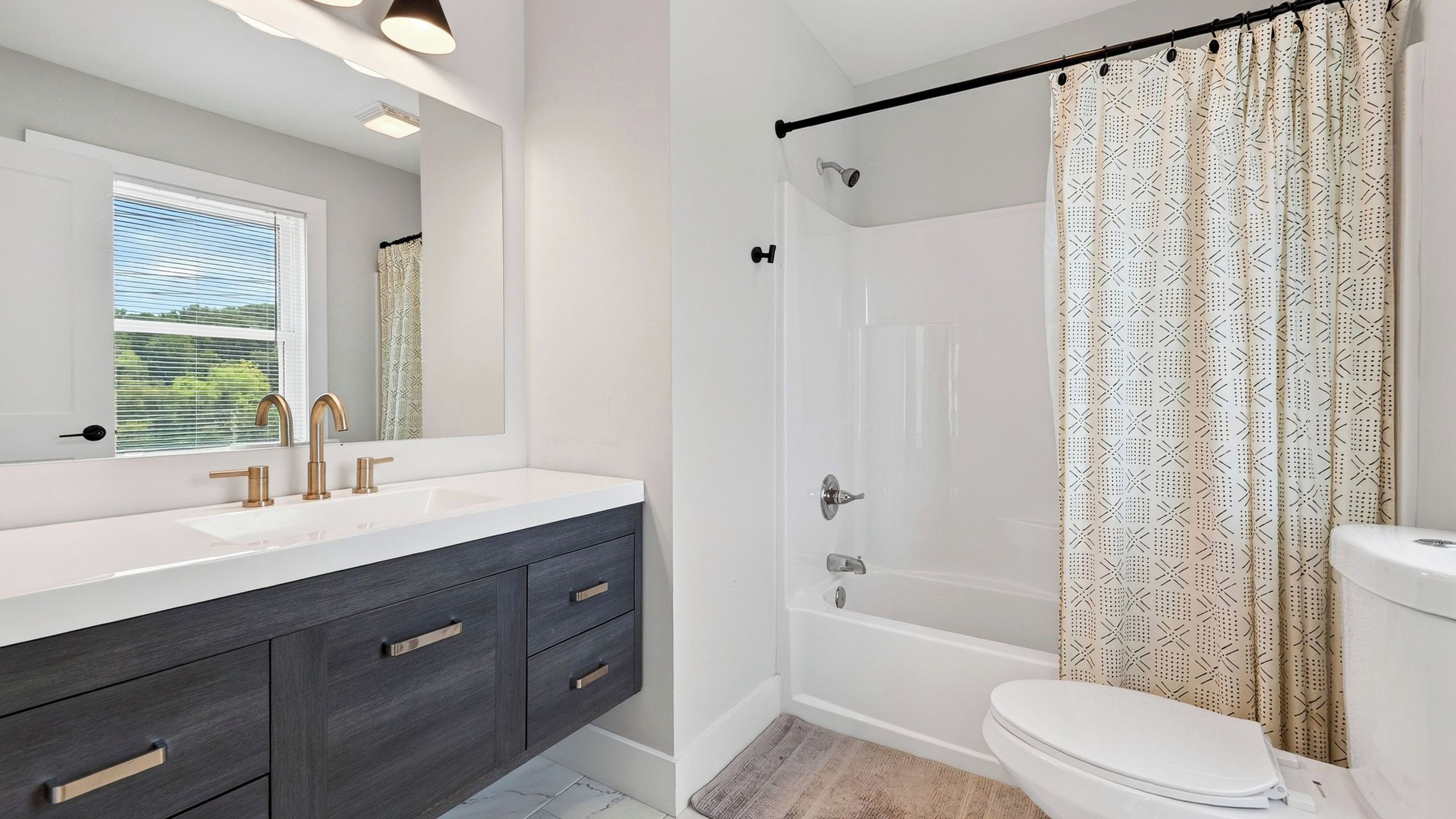 Une salle de bain moderne avec un meuble-lavabo blanc, des armoires en bois foncé, une baignoire et des toilettes.