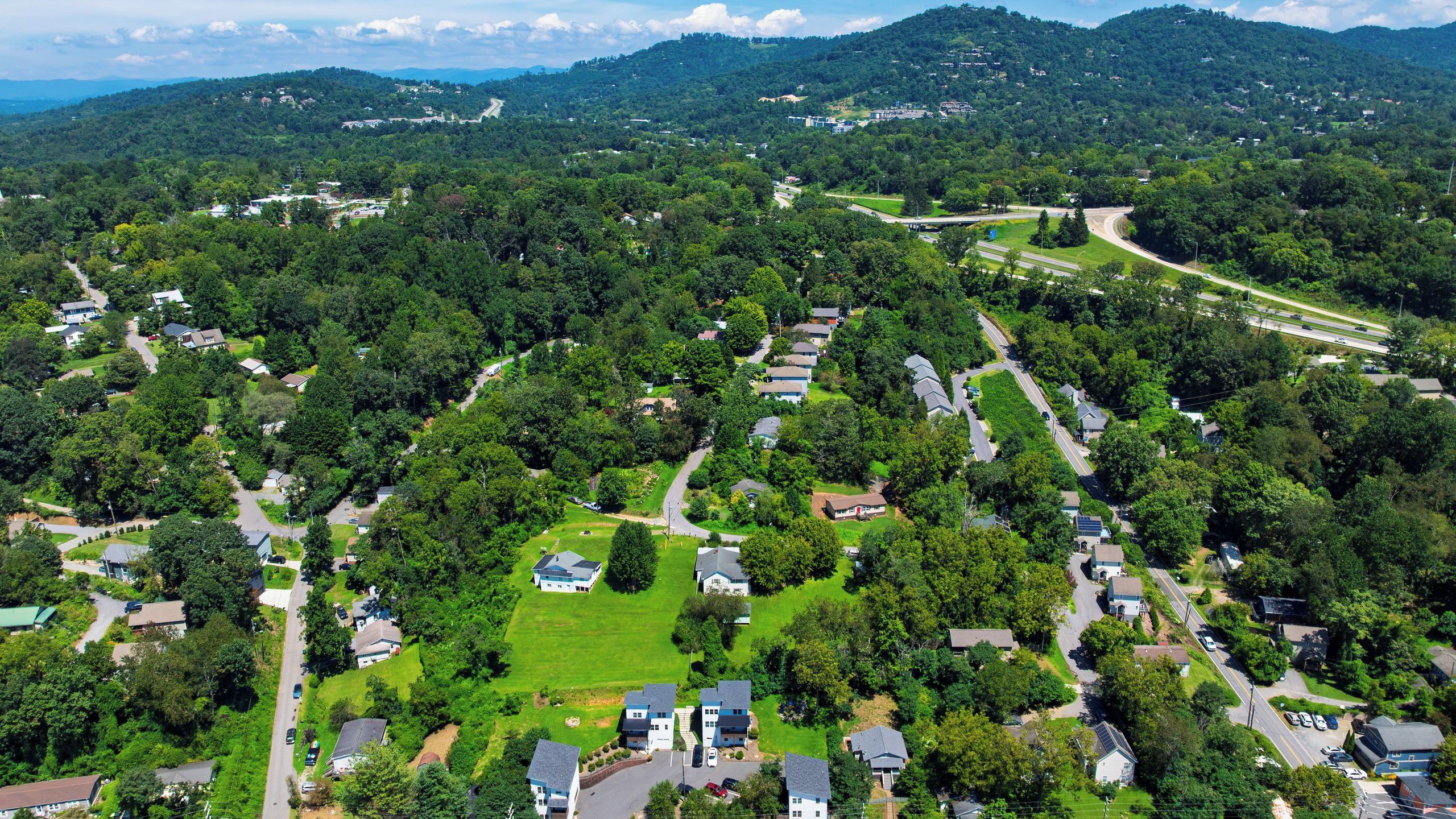 Vue aérienne d’un quartier résidentiel avec des maisons, des routes et de la végétation.