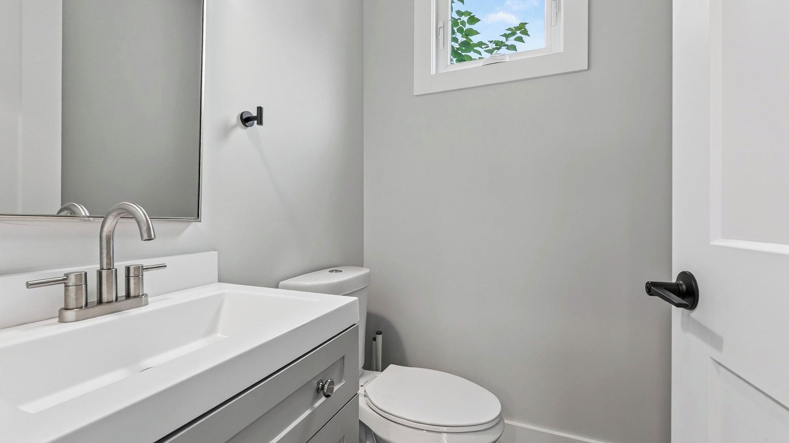 Een moderne badkamer met een witte wastafel, spiegel en toilet.