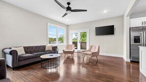 A spacious living room with a dark-colored sofa, two armchairs, a coffee table, and a ceiling fan. - Sage House by Avantstay Balcony + River Views + Full Kitchen River Arts District (Asheville)
