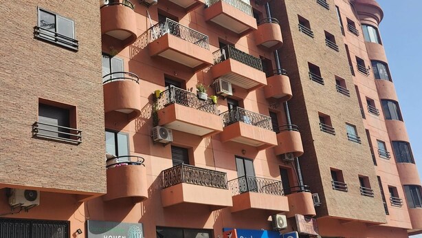 Een meerlaags gebouw met balkons, airconditioners en borden voor een bank en een hotel.