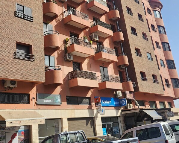 Een meerlaags gebouw met balkons, airconditioners en borden voor een bank en een hotel.