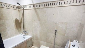 Een badkamer met een bad, een douche en een toilet.