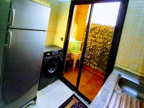 Una cocina compacta con lavadora, refrigerador y pileta.