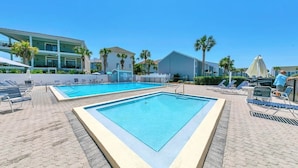 A swimming pool area with lounge chairs and a building in the background. - Lakefront Townhome.  Steps to Private Beach. Large Decks (Destin)