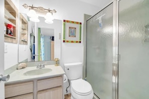 Un baño con lavamanos blanco, inodoro y cabina de ducha.