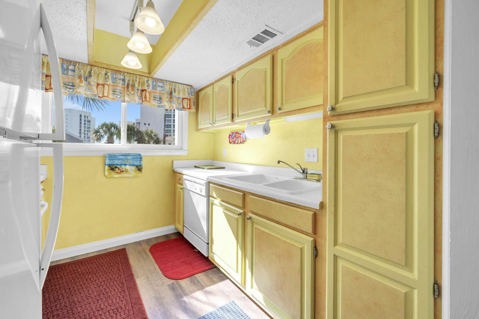 A compact kitchen with a refrigerator, sink, and wooden cabinets.