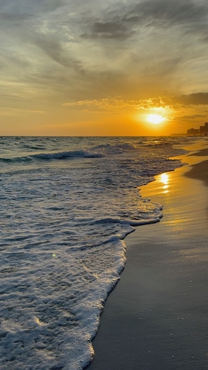 Uma praia com ondas e um pôr do sol.