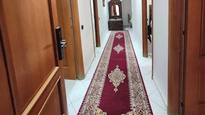 A hallway with wooden doors, a red patterned carpet, and recessed ceiling lighting. - Modern & Spacious Apartment in Guéliz - Parking (Marrakech)