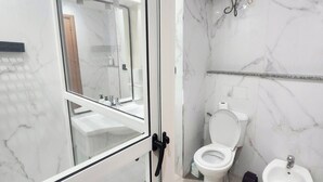 Ett modernt badrum med en duschkabin i glas, en toalett, en bidé och en luftrenare som är monterad på väggen.