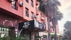 En byggnad med flera luftkonditioneringsaggregat, en skylt för en restaurang och en palm på förgrunden.