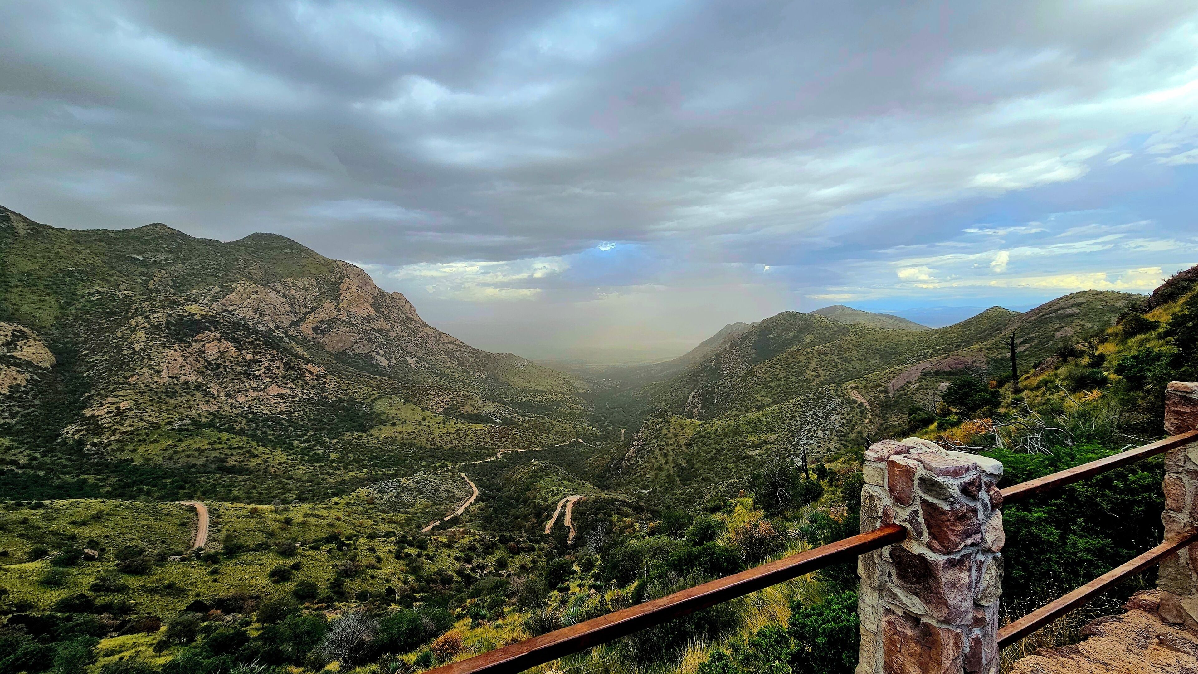 A mountainous landscape with a dirt path leading through a valley.
