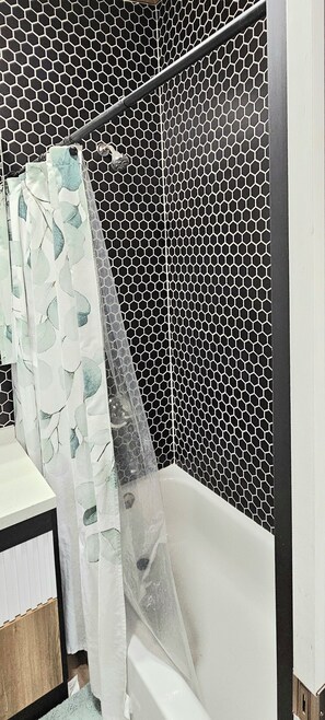 Un bagno con tenda da doccia, vasca e rivestimento in piastrelle.