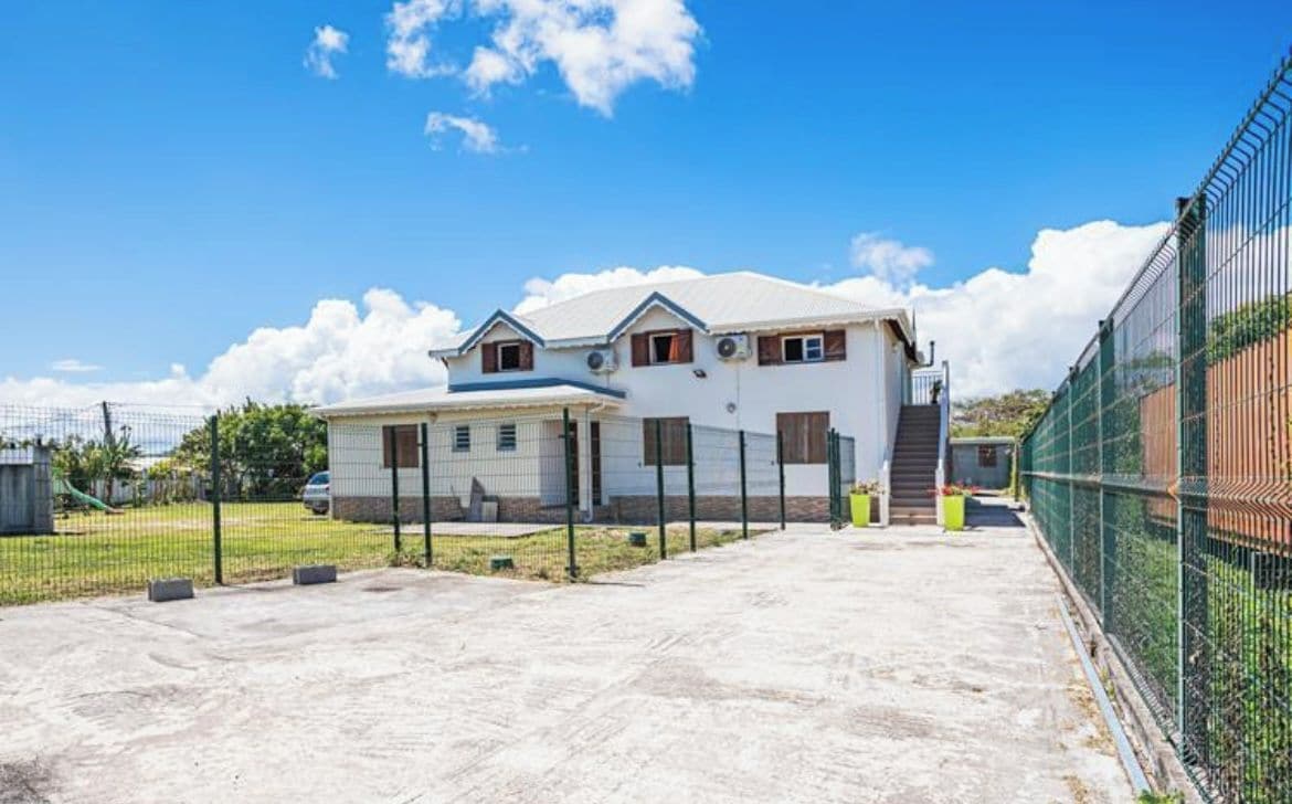 A two-story house with a garage, a fenced yard, and a clear sky.