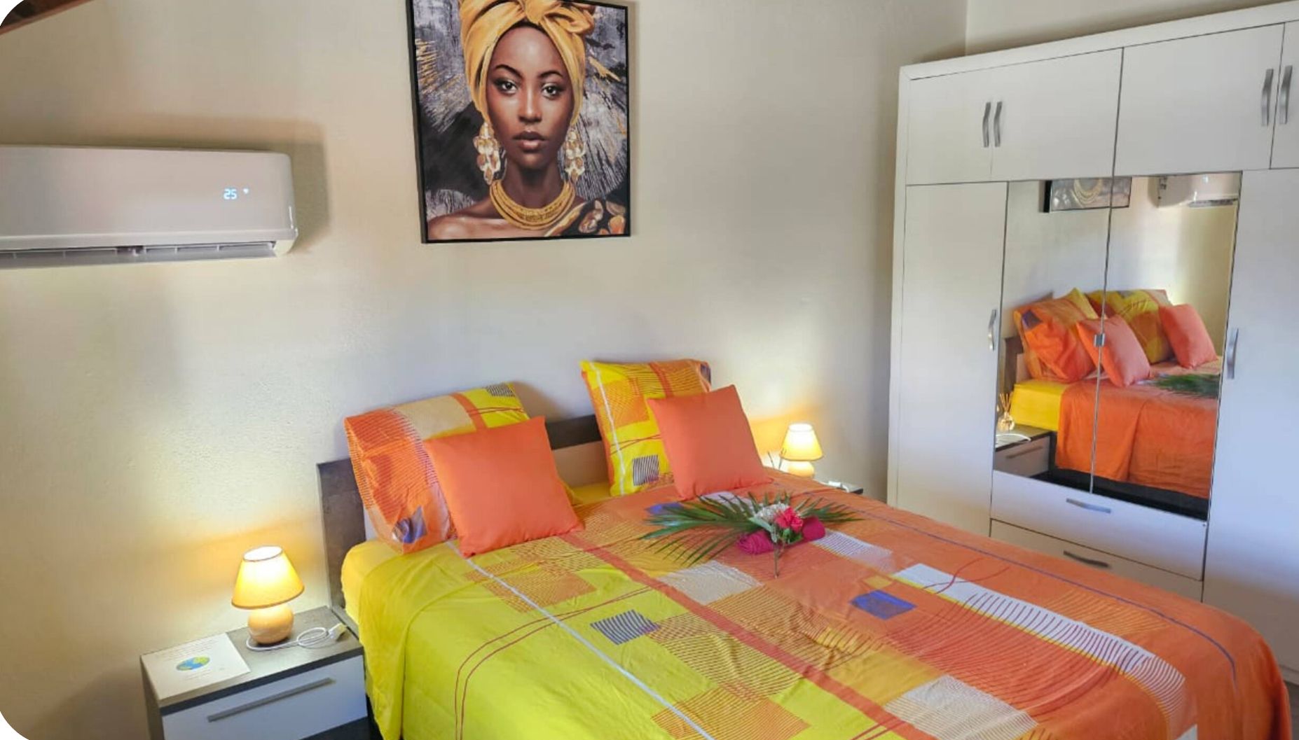 Une chambre d’hôtel comprenant un lit, une table de chevet, une lampe, un climatiseur, une armoire et un tableau au mur.