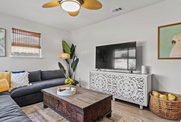 A living room with a sofa, a coffee table, a television, and decorative items.
