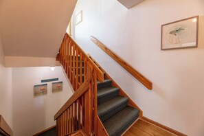 A wooden staircase with carpeted steps leading to a landing. - Sandpiper - Whalehead, Semi-Oceanfront, Pool, Hot Tub, Pets OK, YR Flex Stays (Corolla)