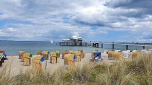 Ein Strand mit Strandkörben und einem Steg, der sich ins Wasser erstreckt.