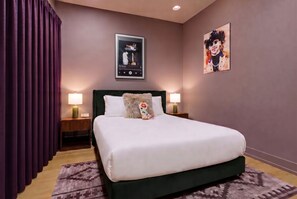 A hotel room with a bed, two bedside lamps, a framed picture on the wall, and a window with curtains. - Ultimate Nashville Fun House ~ Rooftop Dance Floor | Hot Tub | Sauna | Games | Sleeps 16 (Nashville)