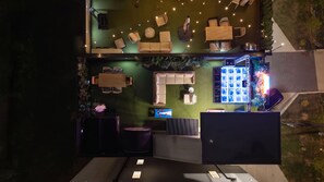 Eine Vogelperspektive eines Dachterrassen-Lounges mit Außenmöbeln, einem Poolbereich und einer Bar.