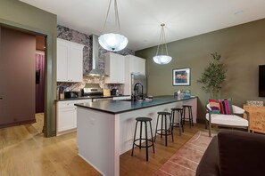 Une cuisine moderne dotée d’un îlot central, de tabourets de bar et d’un coin repas comprenant un canapé et des chaises.