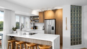 Een moderne keuken met een groot eiland, roestvrijstalen apparatuur en houten details.