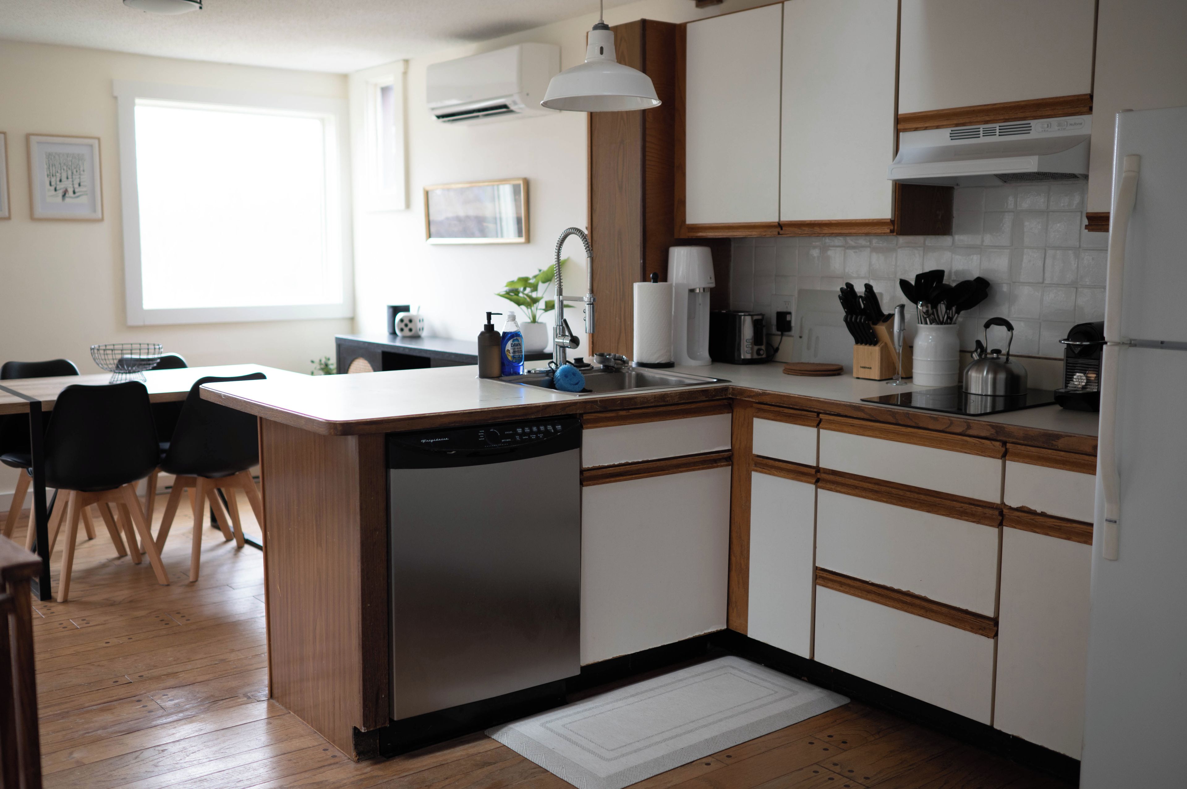 A modern kitchen with wooden cabinets, a dishwasher, and a dining area with chairs.