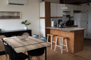 Eine moderne Küche mit einer Holztischinsel, Barhocker, einer Hängelampe und einem Blumentopf.
