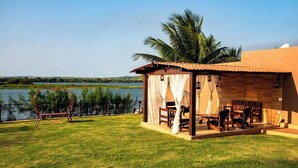 Una casetta sulla spiaggia con un patio, una sedia a forma di cuore e vista sull'acqua.