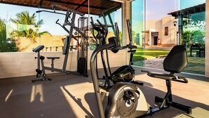 Una palestra con attrezzature per esercizi, tra cui una cyclette e macchinari per pesi, in un edificio moderno con ampie finestre.