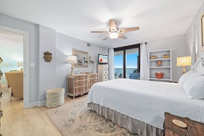 A bedroom with a bed, a dresser, a vanity, a ceiling fan, and a view of the ocean. - Gulf Front | Huge Balcony | Direct Beach Access | BEACHBALL PROPERTIES (Orange Beach)