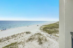 A beach with a clear sky, a sandy shore, and a few umbrellas. - Gulf Front | Huge Balcony | Direct Beach Access | BEACHBALL PROPERTIES (Orange Beach)